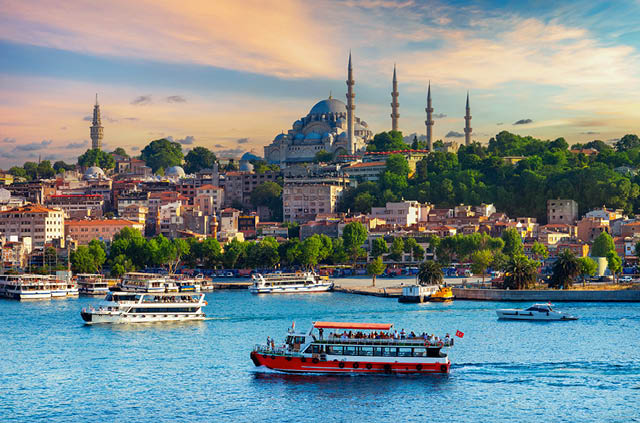 A view of a mosque and other architectural highlights in Istanbul with boats and a body of water in the foreground.