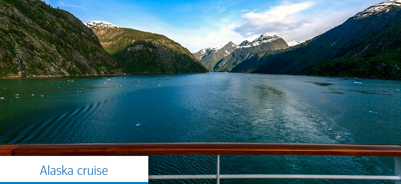 Text reads, “Alaskan cruise.” View of a large body of water and mountains, looking out past the handrail of a boat.