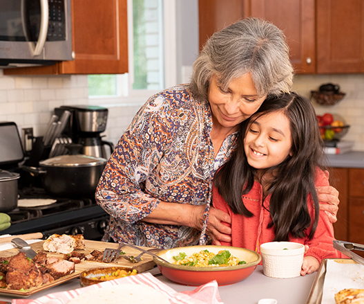 Older Latina woman with garnd daughter preparing food in the kitchen