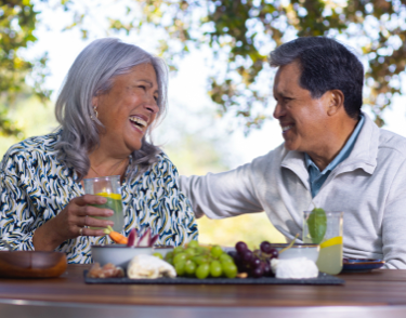 Older Latina woman with middle age Latino man sharing lunch outside