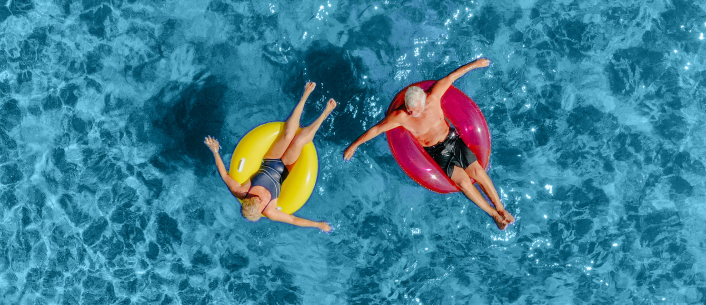 Man and woman floating on colorful innertubes in a pool